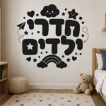 מדבקת טקסט עברי צבעוני על קיר בחדר ילדים עם מיטת עץ וצעצועים צבעוניים