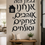 מדבקת טקסט שחורה עם טיפוגרפיה אלגנטית ואייקון בית קטן על קיר בסלון חמים עם ספה.