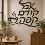 מדבקת כוס קפה וטקסט עברי על קיר בסלון ליד כורסה אפורה ושולחן קפה עץ.