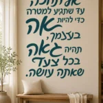 מדבקת קליגרפיה עברית שחורה מודגשת על קיר לבן בסלון עם ספה אפורה ושולחן עץ כהה.