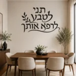 מדבקת קליגרפיה עברית עם עלים על קיר בסלון עם ספה אפורה ותמונות משפחתיות.