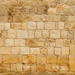 טפט קיר אבן עם בלוקים מלבניים בגווני בז' וחום בהיר, יוצר מראה כפרי.