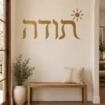 מדבקה עם טקסט עברי ושמש קטנה על קיר בחדר ילדים עם מדף צעצועים וספרים.
