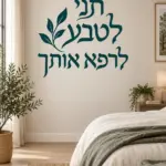 מדבקת טקסט עברי עם עלים על קיר בחדר ילדים עם מדפים וספרים צבעוניים, אור טבעי נכנס מהחלון.