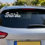 מדבקה עם הכיתוב 'קסם המדבר' על השמשה האחורית של רכב חום, בתמונת חוץ.