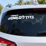 מדבקה עם הכיתוב 'בדרכים' וסילואטת רכב קלאסי על השמשה האחורית של רכב שחור ברחוב עירוני.