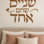 מדבקת קליגרפיה עברית עם לבבות על קיר בחדר ילדים עם צעצועים צבעוניים ומנורת לילה.