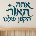 מדבקה עם כיתוב עברי מודגש וכוכב קטן על קיר בחדר ילדים עם שולחן משחקים צבעוני.