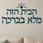 מדבקת טקסט עברי עם שמש על קיר בחדר ילדים עם צעצועים צבעוניים וספרים.