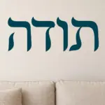 מדבקה עם אותיות עבריות על קיר בחדר ילדים עם רהיטים צבעוניים ואור טבעי.