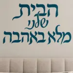 מדבקה עם קליגרפיה עברית על קיר בחדר ילדים עם צעצועים על המדף ותאורה רכה.
