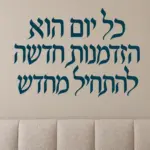 מדבקת קליגרפיה עברית שחורה על קיר בסלון עם ספה נוחה וצמחי בית ירוקים ברקע