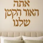 מדבקת טקסט עברי על קיר בסלון עם ספה אפורה ושולחן קפה מעץ כהה