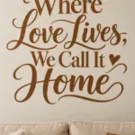 מדבקה עם כיתוב דקורטיבי 'Where Love Lives, We Call It Home' על קיר בסלון עם כורסה אפורה ושטיח צבעוני.
