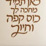 מדבקת טקסט עברי על קיר בחדר מגורים עם ספה לבנה ושולחן עץ כהה