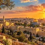 כיפה מוזהבת ומבנים עתיקים באבן מוקפים בגוונים חמים של שקיעה וירק שופע.
